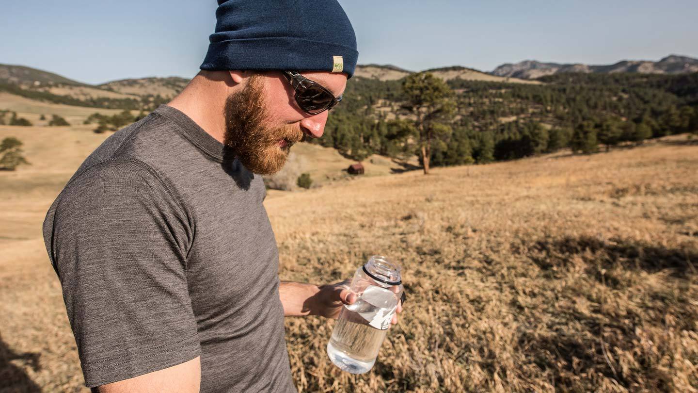 man in field wearing minus33 merino wool lightweight t-shirt and beanie