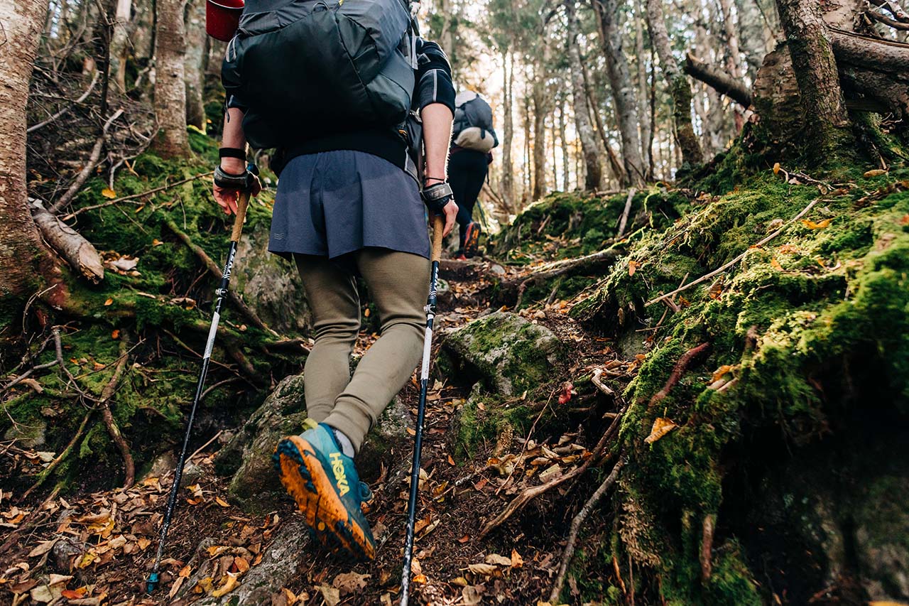 man hiking up a mountain wearing lightweight merino wool long johns under his shorts