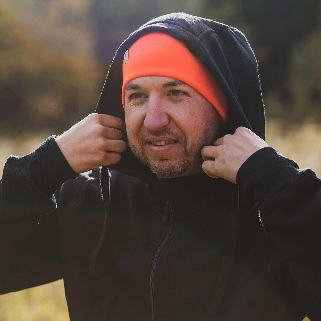 A man adjusts his hood on the heavyweight brushed wool Kodiak Fleece Hoodie, crafted with thumbholes and a drawstring to bundle you up for wicked cold days! #color_black