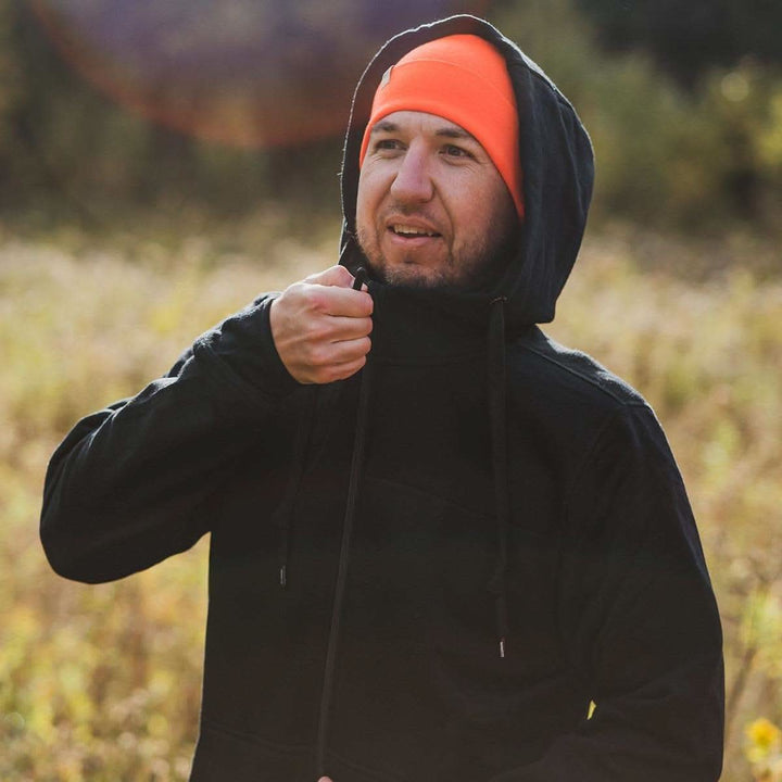 A man zips up his heavyweight brushed wool Kodiak Fleece Hoodie, crafted with thumbholes and a drawstring to bundle you up for wicked cold days! #color_black