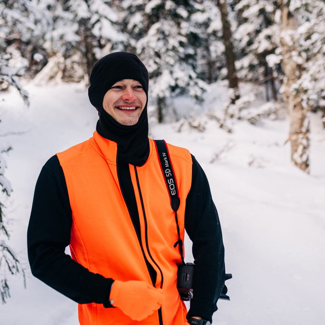 A man models the heavyweight merino wool full-zip vest #color_blaze-orange