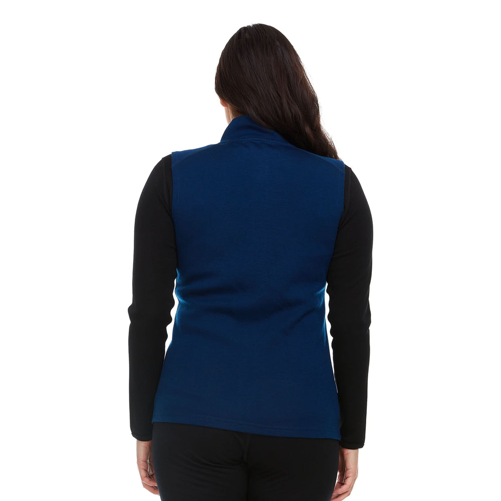 A woman models a hundred percent merino wool heavyweight full zip vest. This outer layer features a two and a half inch mock neck collar and two zippered pockets. #color_navy