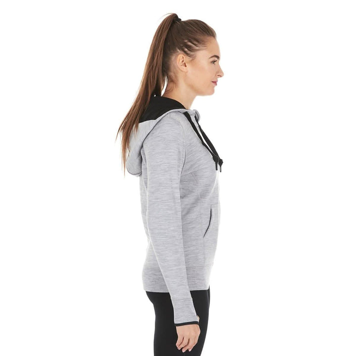 A woman models the heavyweight merino wool brushed fleece hoodie. The hoodie features a large hood with drawstrings, thumbholes, two pockets, and an interior stash pocket inside. #color_ash-gray