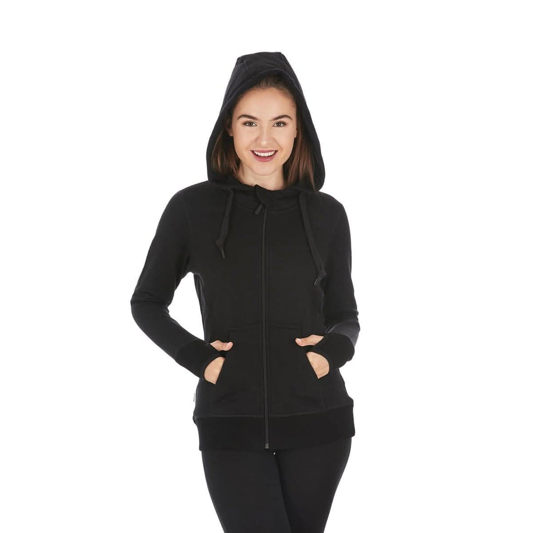 A woman models the heavyweight merino wool brushed fleece hoodie. The hoodie features a large hood with drawstrings, thumbholes, two pockets, and an interior stash pocket inside. #color_black