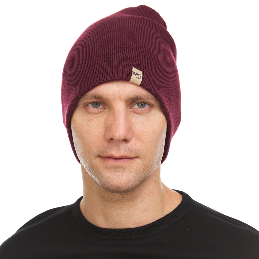 A man models a heavyweight, super soft, one hundred percent merino wool beanie. This heavyweight beanie is the warmest hat that we offer, perfect for hiking through the White Mountains, or sitting at a bonfire in January. #color_burgundy