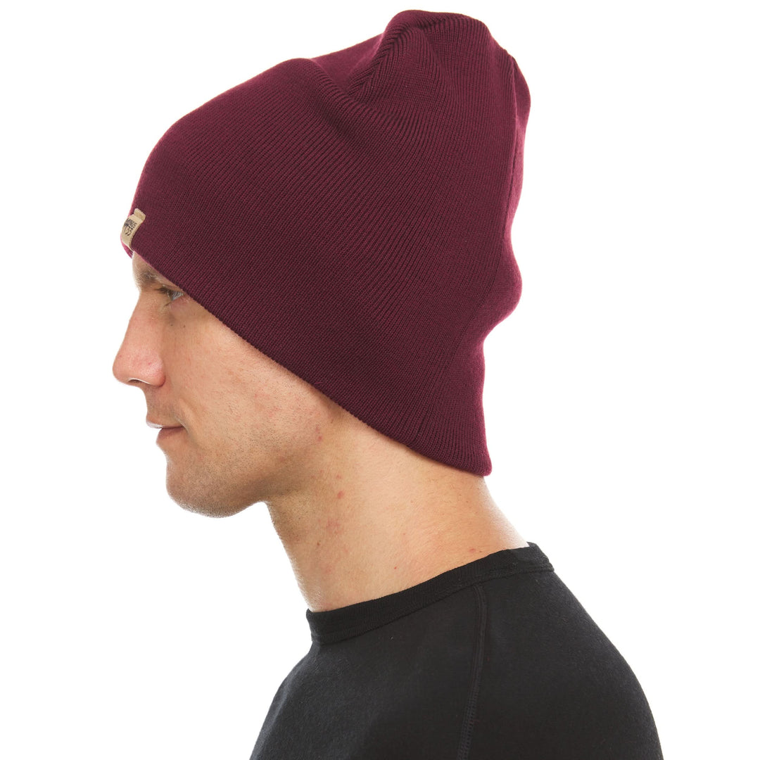 A man models a heavyweight, super soft, one hundred percent merino wool beanie. This heavyweight beanie is the warmest hat that we offer, perfect for hiking through the White Mountains, or sitting at a bonfire in January. #color_burgundy