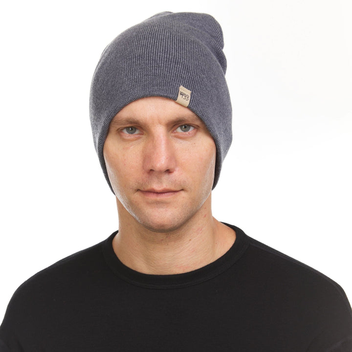 A man models a heavyweight, super soft, one hundred percent merino wool beanie. This heavyweight beanie is the warmest hat that we offer, perfect for hiking through the White Mountains, or sitting at a bonfire in January. #color_charcoal-gray