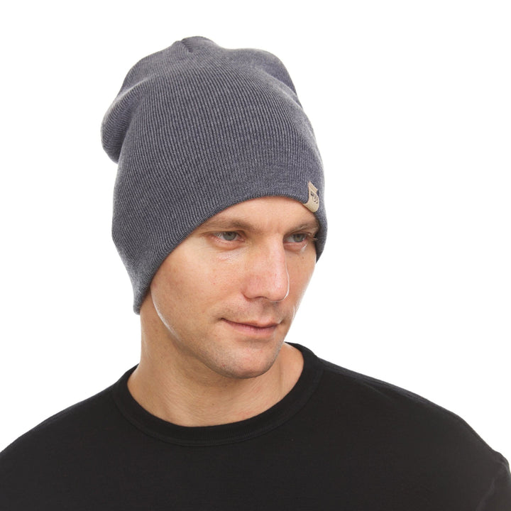 A man models a heavyweight, super soft, one hundred percent merino wool beanie. This heavyweight beanie is the warmest hat that we offer, perfect for hiking through the White Mountains, or sitting at a bonfire in January. #color_charcoal-gray