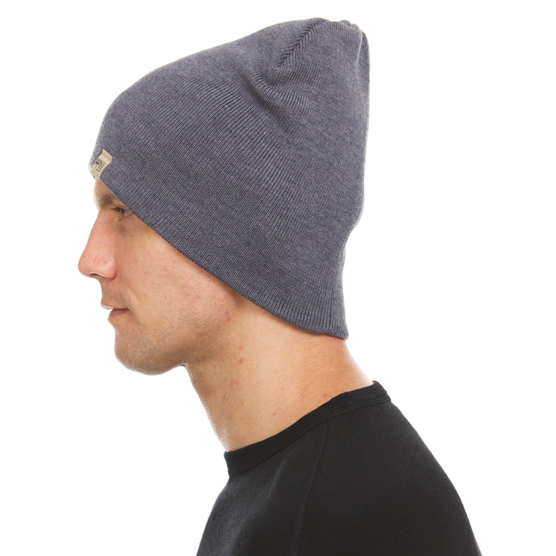 A man models a heavyweight, super soft, one hundred percent merino wool beanie. This heavyweight beanie is the warmest hat that we offer, perfect for hiking through the White Mountains, or sitting at a bonfire in January. #color_charcoal-gray