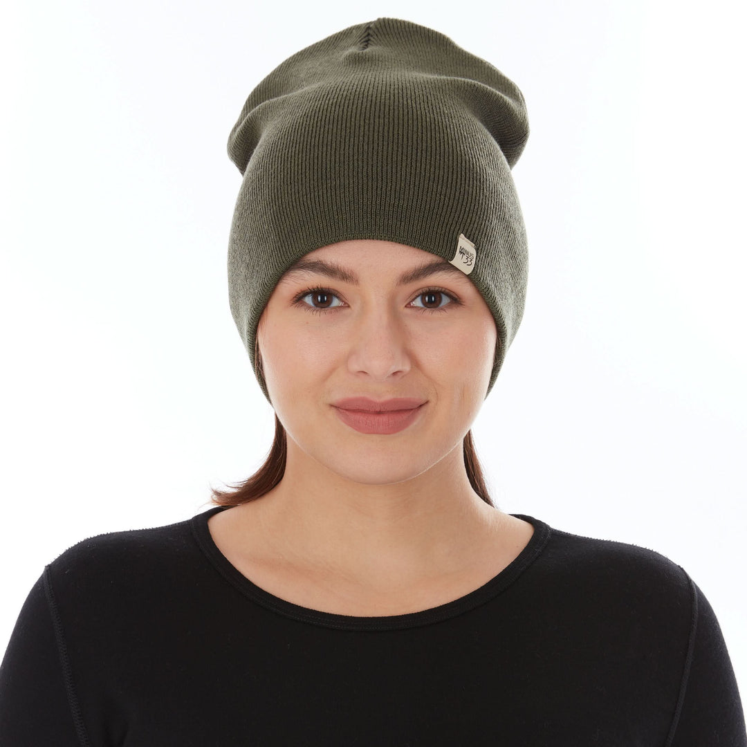 A woman models a heavyweight, super soft, one hundred percent merino wool beanie. This heavyweight beanie is the warmest hat that we offer, perfect for hiking through the White Mountains, or sitting at a bonfire in January. #color_olive-drab-green