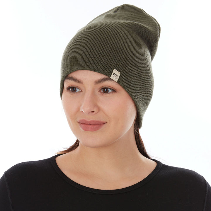 A woman models a heavyweight, super soft, one hundred percent merino wool beanie. This heavyweight beanie is the warmest hat that we offer, perfect for hiking through the White Mountains, or sitting at a bonfire in January. #color_olive-drab-green