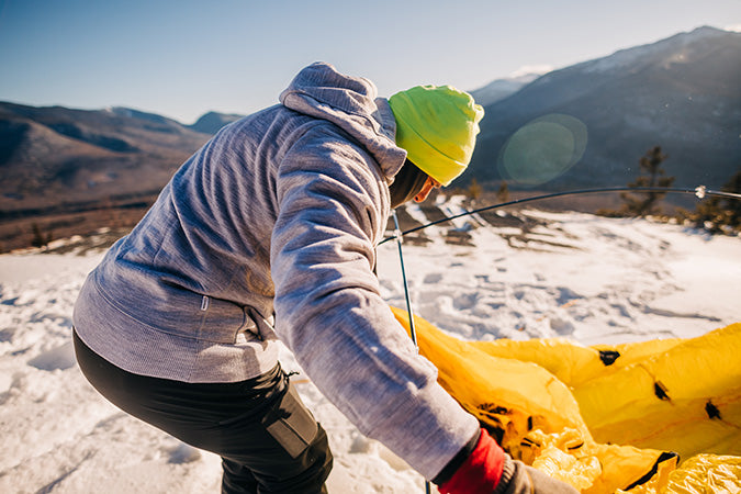 man setting up tent wearing kodiak fleece hoodie heavyweight