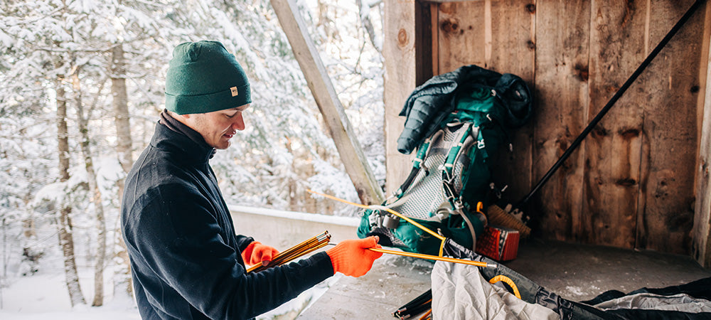man setting up tent wearing wilderness expedition