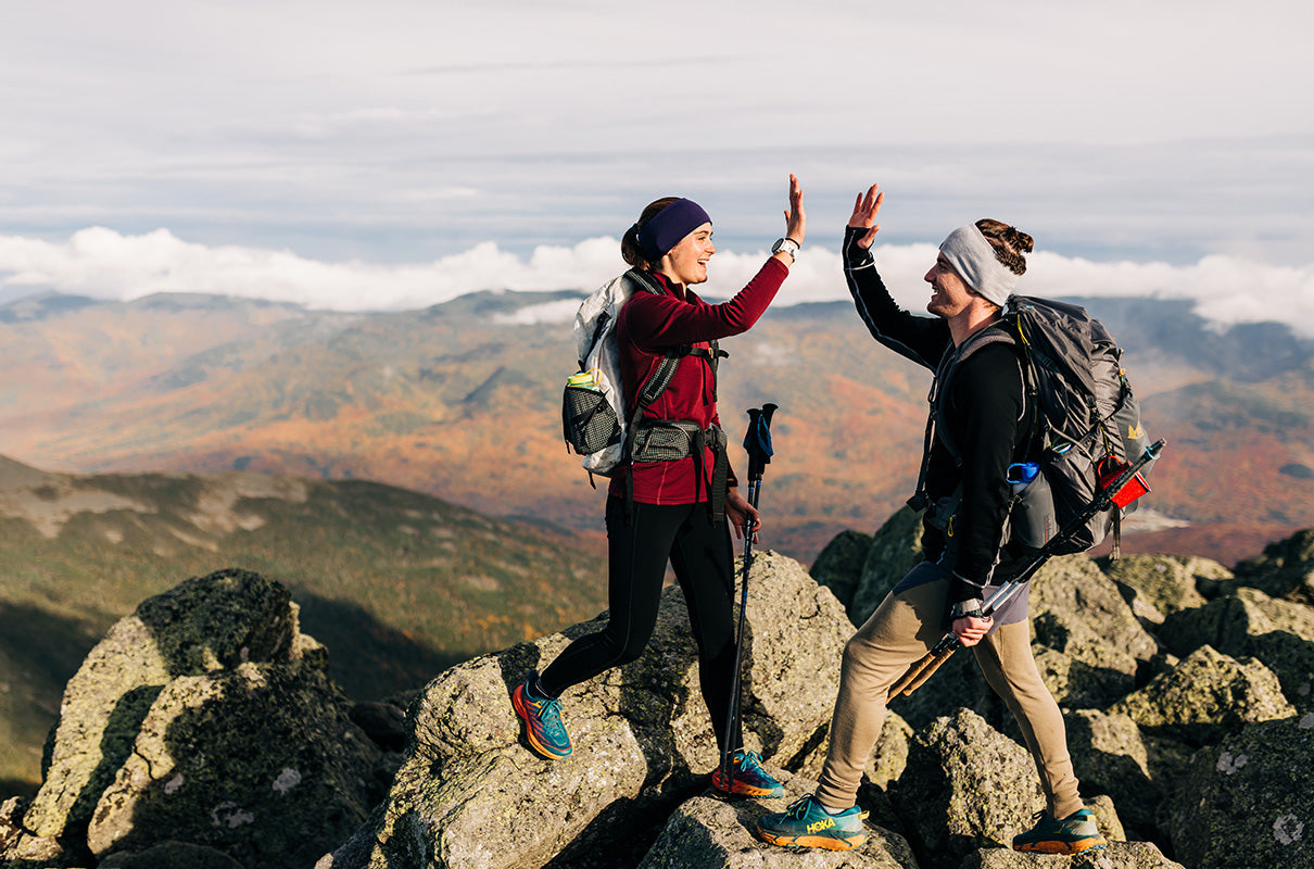 man and women hiking in the fall wearing midweight tops and bottoms