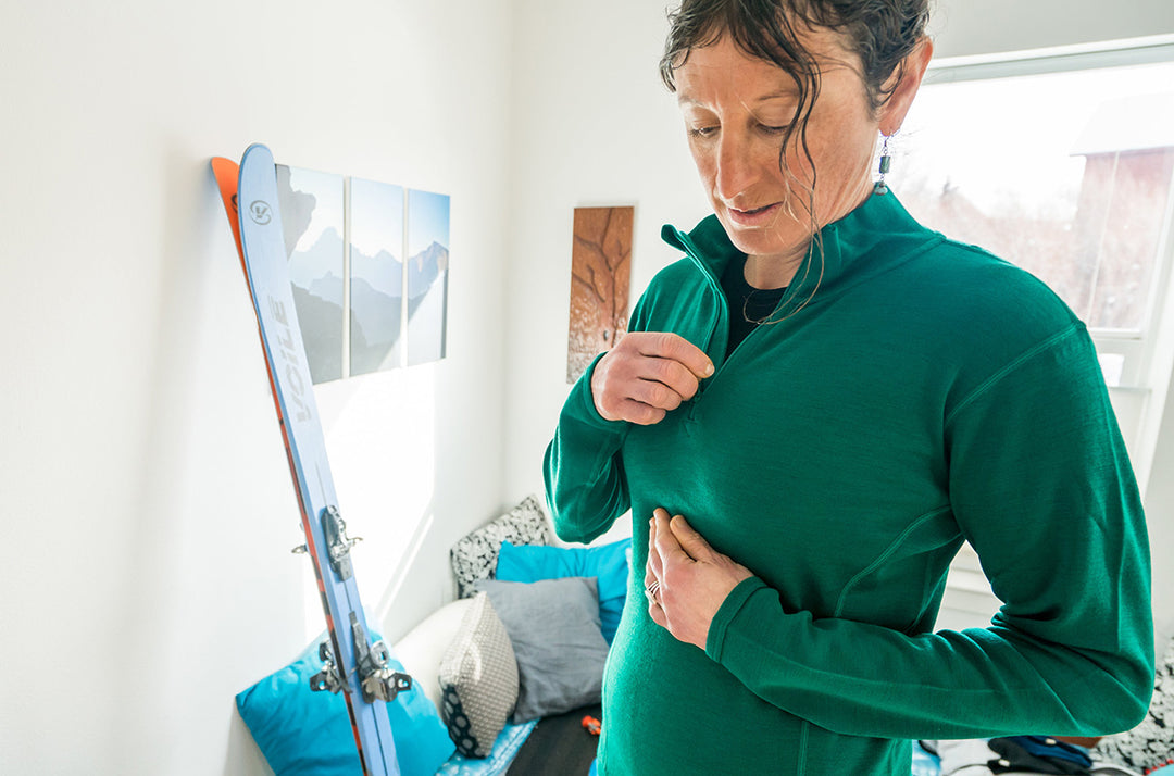 woman getting ready to go skiing zipping up merino wool midweight quarter zip