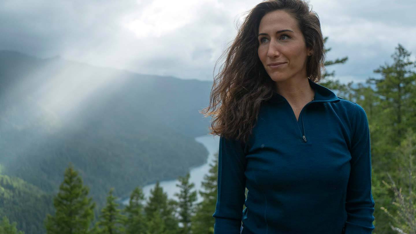 woman on mountaintop wearing minus33 merino wool midweight 1/4 zip mid layer shirt