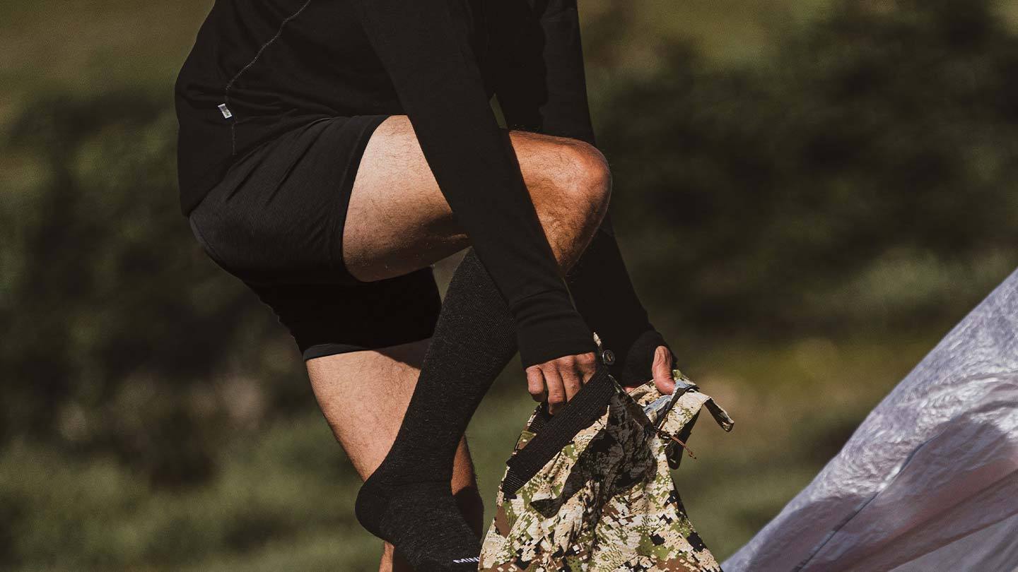 man putting on pants while wearing minus33 merino wool lightweight boxer brief underwear