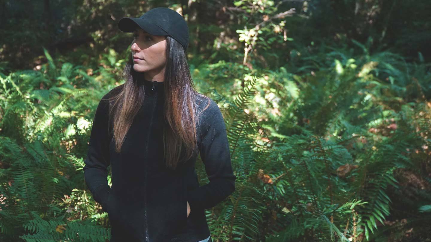 woman in the forest wearing minus33 wilderness expedition full zip pullover