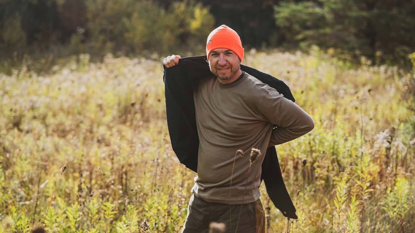 man putting on sweatshirt over lightweight minus33 merino wool crew base layer
