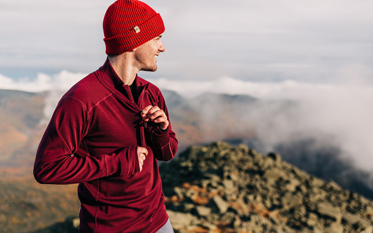 man hiking in the fall wearing midweight 100% merino wool burgundy 1/4 zip