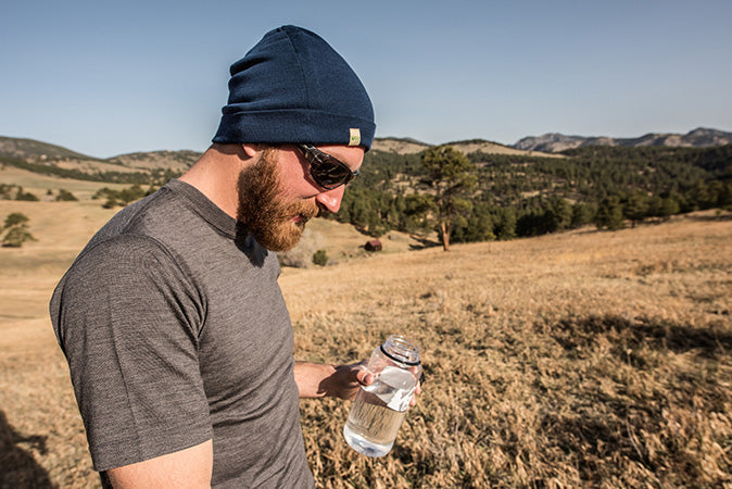 person putting on 100 merino wool beanie while wearing a balaclava