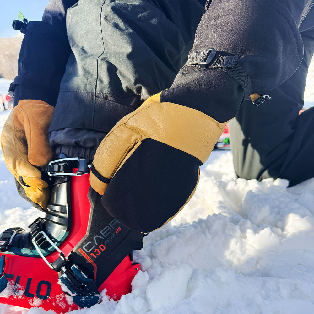 ski boot in the snow wearing yellow and black waterproof winter ski gloves 