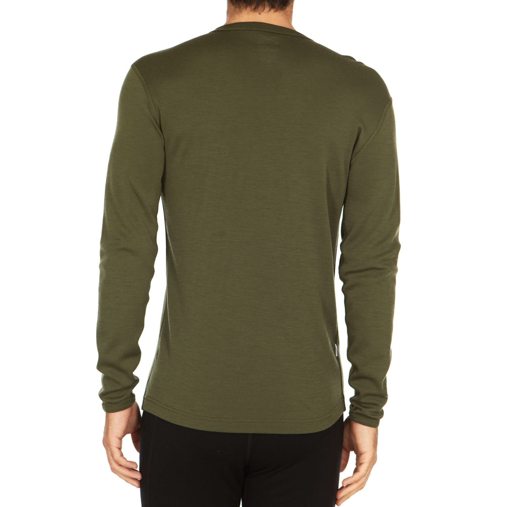 A man models a super soft, long sleeved merino wool thermal base layer crew. This top makes for a perfect first layer on a winter hike, or a nice casual wear on the chilly days of autumn and spring. #color_olive-drab-green