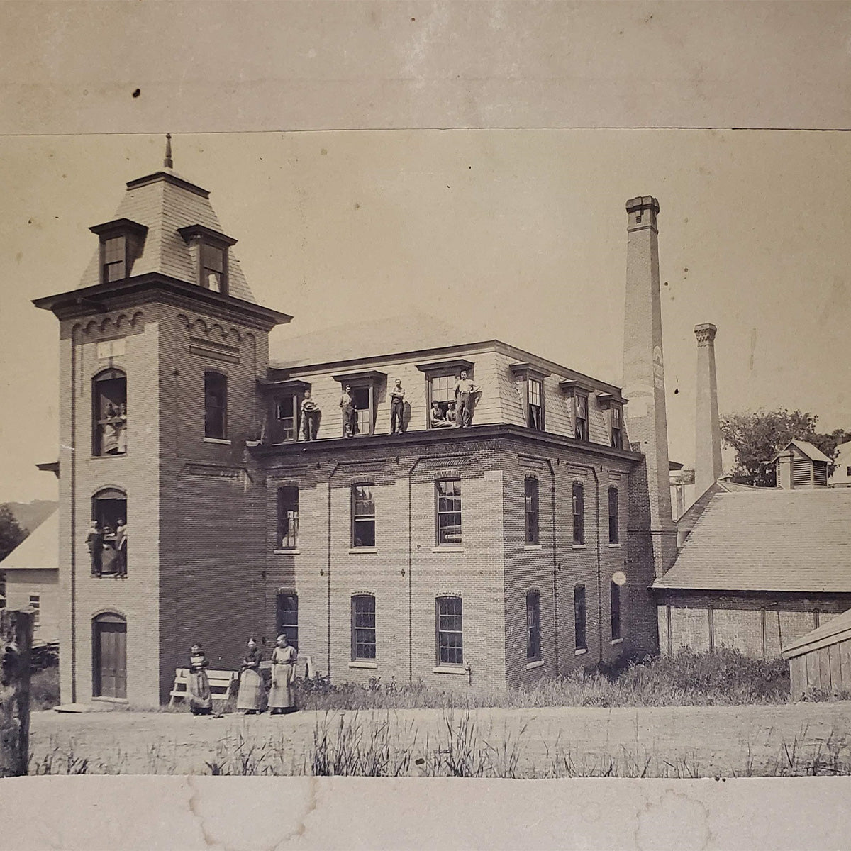 Vintage black-and-white photograph of a multistory building with people standing on its roof.