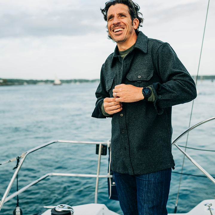 Man buttons heavy wool shirt jac while sailing #color_charcoal-gray
