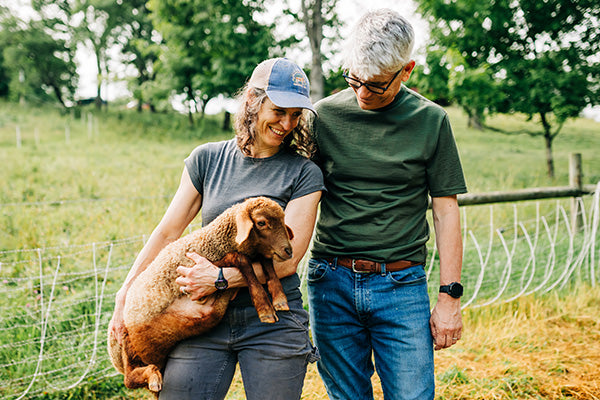 Holding a baby sheep in merino wool t shirt and merino wool crew shirt