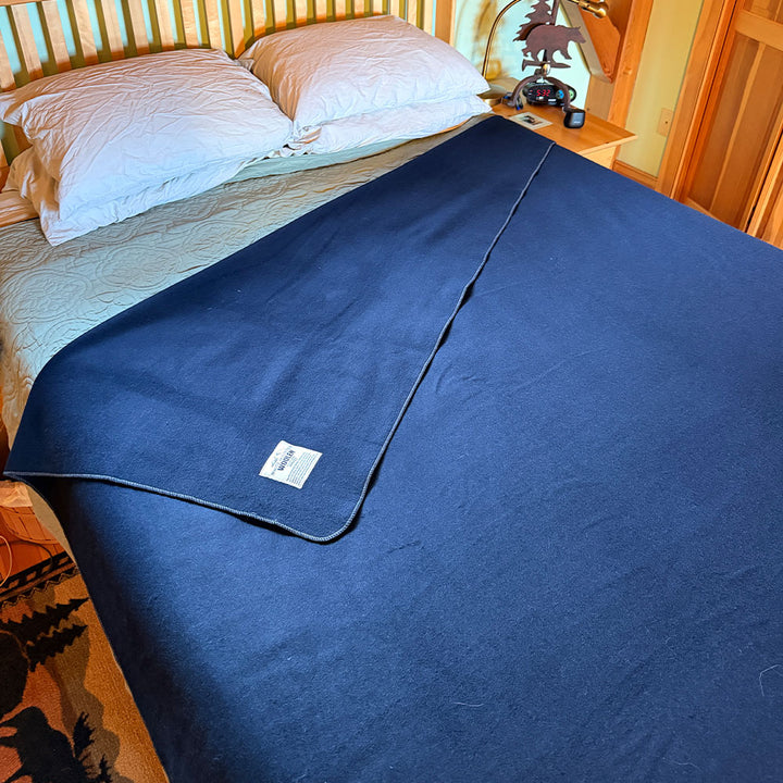 Blue blanket draped over a bed in a bedroom setting queen sized merino wool blanket 