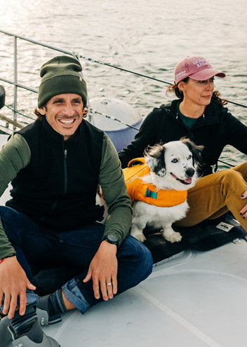 two people sitting on a boat in their merino wool clothing that keeps them warm while sailing