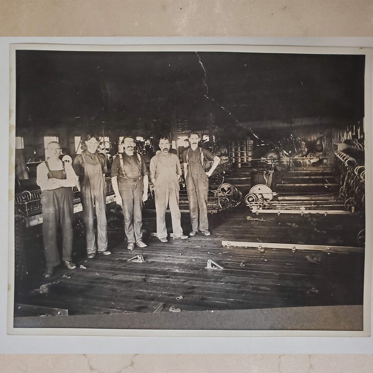Black-and-white photograph of five men working together in a workshop.