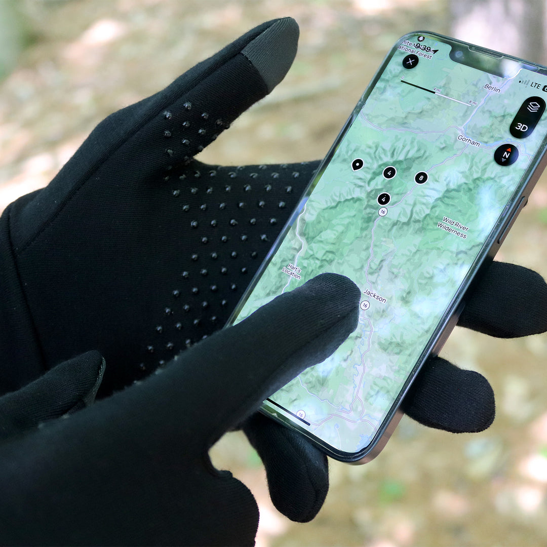 Man wearing black Merino touchscreen gloves with no slip dots scrolls map on phone #color_black