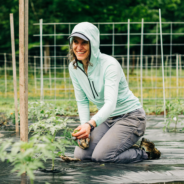 Woman gardening wearing a microweight Merino wool sun hoodie  #color_mint
